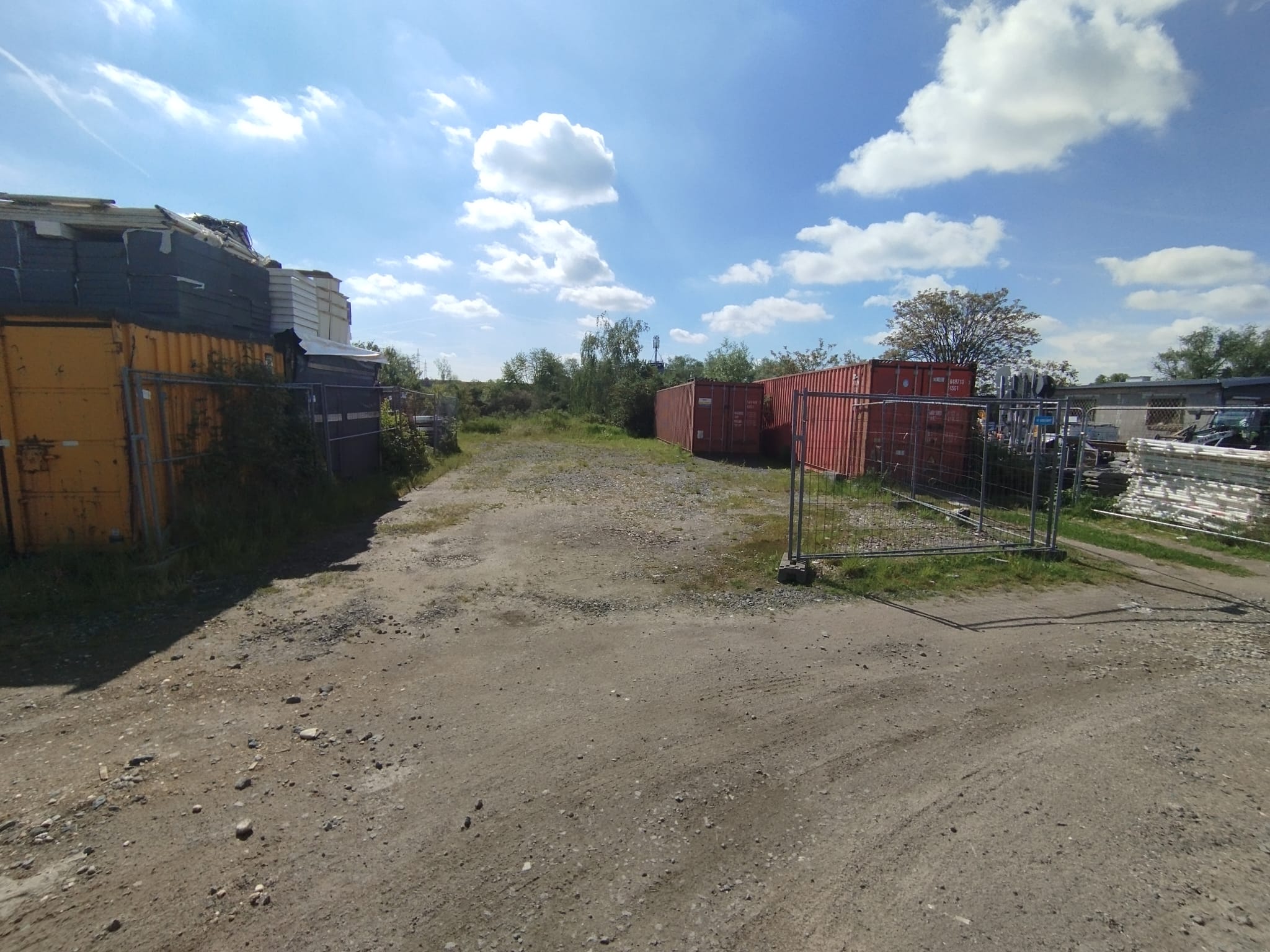 Ein Schrottplatz mit roten Containern und bunten Kisten unter blauem Himmel
