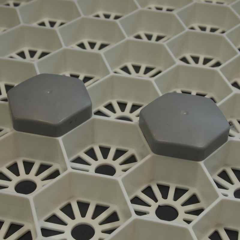 Zwei graue achteckige Kappen auf einer beigen wabenfoermigen Gitterstruktur